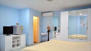 A hotel room with a bed, a TV on a white cabinet, a mirror, and a wall-mounted air conditioner. - Aree 's House (Hua Hin)