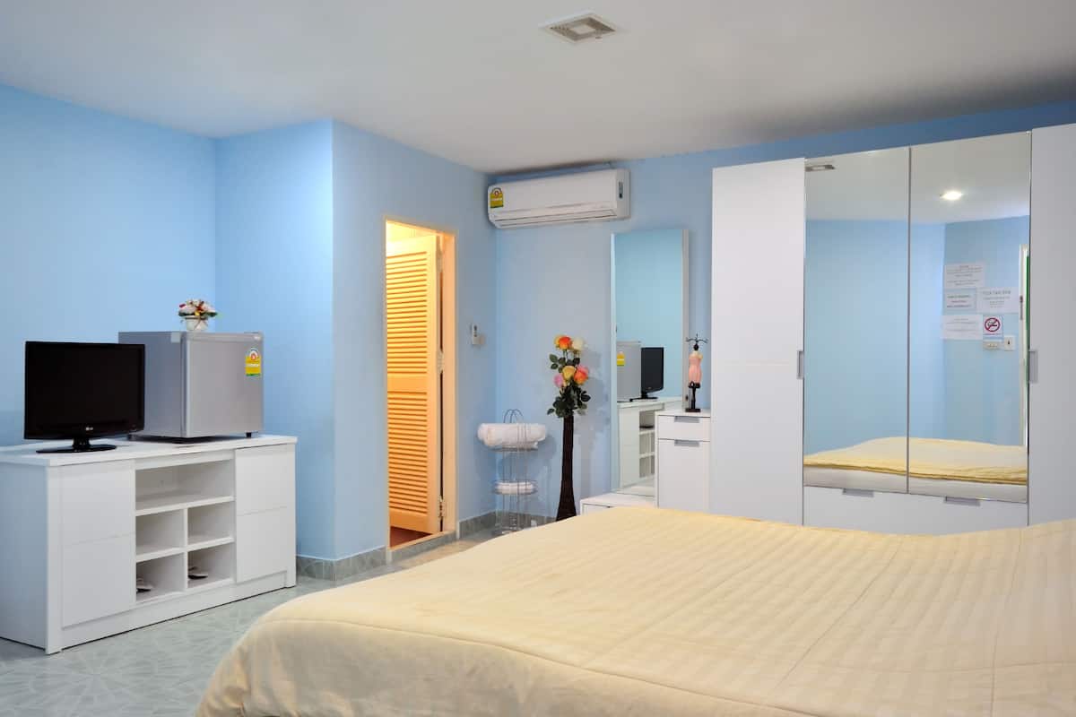 Habitació d'hotel amb un llit, una televisió damunt un moble blanc, un mirall i aire condicionat fixat a la paret.