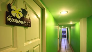 A hallway with green walls and a wooden door with a sign. - Aree 's House (Hua Hin)