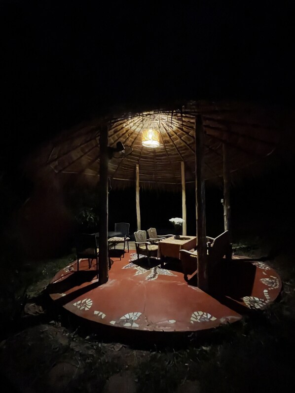 A circular outdoor seating area with a thatched roof, a table, and chairs. - Chiang Dao Roundhouses (Chiang Dao)