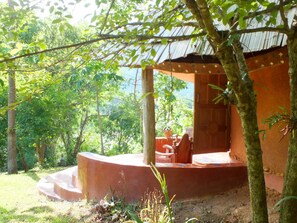Relax in a serene natural setting surrounded by lush greenery and trees, with a seating area featuring a bench and table.