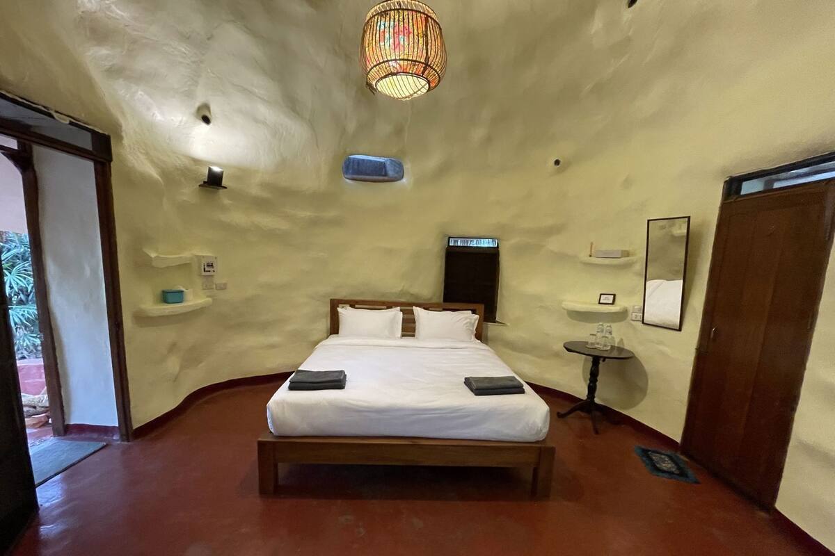 A bedroom with a bed, bedside tables, a mirror, and a unique ceiling design.