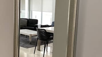 Een spiegel met een ribbelig frame dat een moderne woonkamer weerspiegelt, met een bank, een tafel en stoelen.