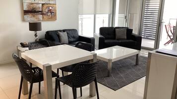 A modern living room with a dining table, two sofas, and a coffee table.