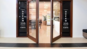 Une entrée de café moderne, avec des portes vitrées et une enseigne indiquant « OCEAN 205 CAFE ».