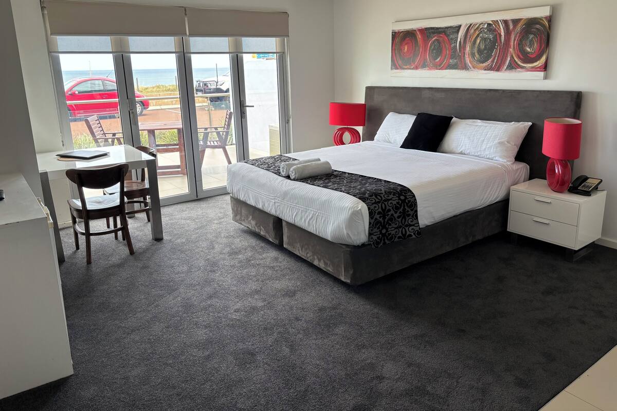Habitación de hotel moderna con una cama grande, un escritorio y vistas a través de un ventanal corredero.