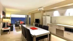 Une cuisine moderne avec un coin repas, un téléviseur et une vue sur la mer.