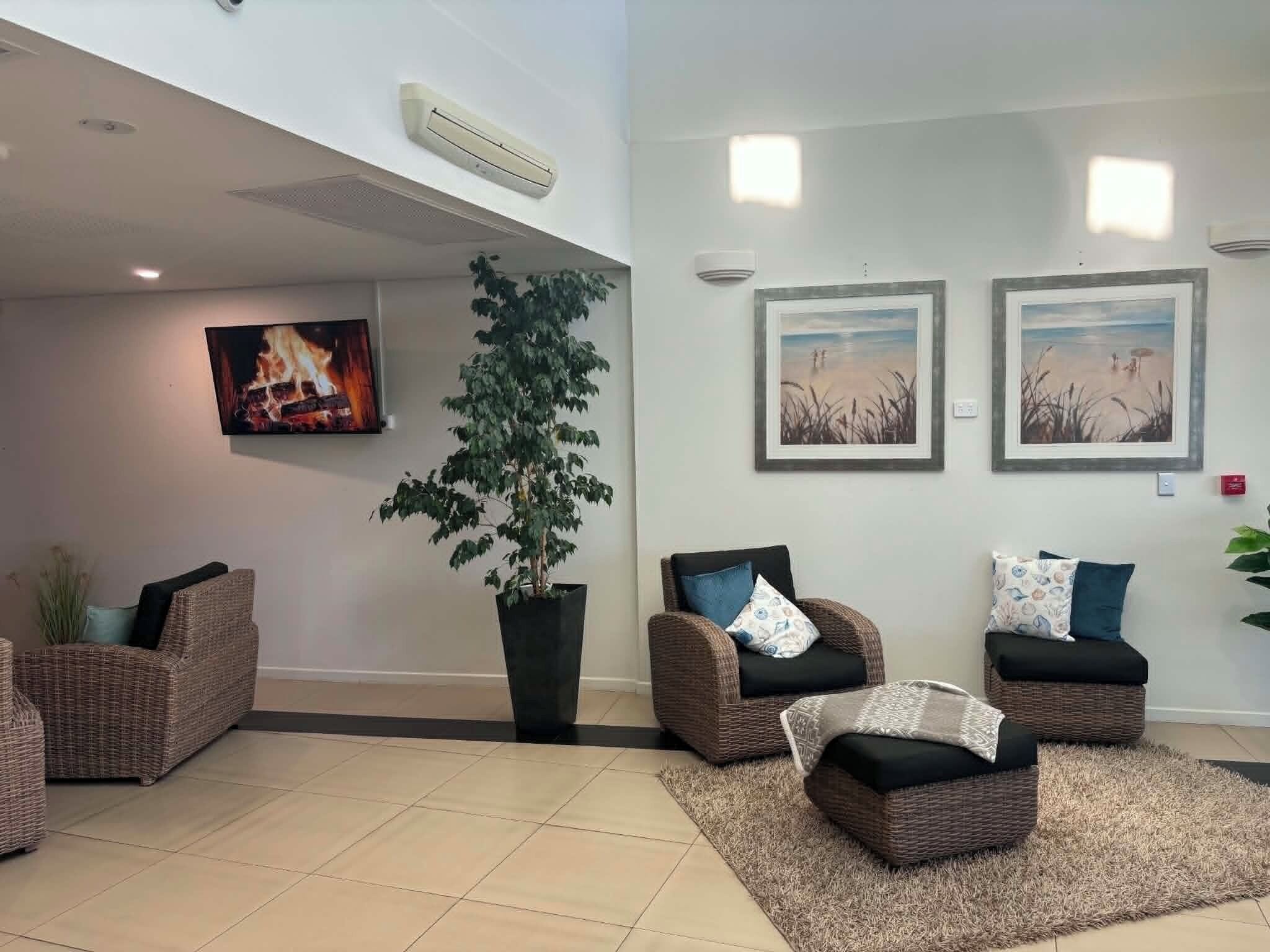 A living area with wicker furniture, a large potted plant, and wall-mounted artwork.