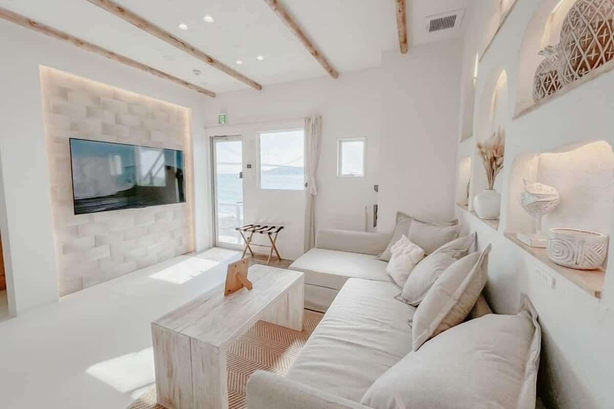 Una sala de estar moderna con un televisor de pantalla plana, un sofá, una mesa de centro y vista al mar.