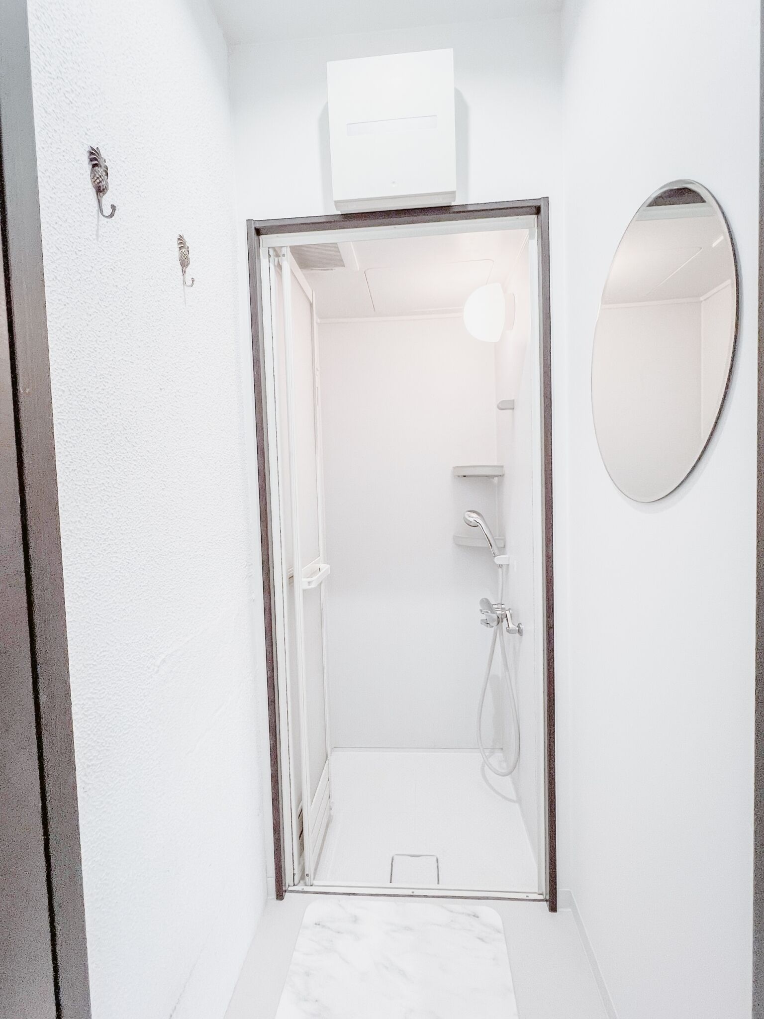 A modern bathroom with a shower, a mirror, and a towel rack.