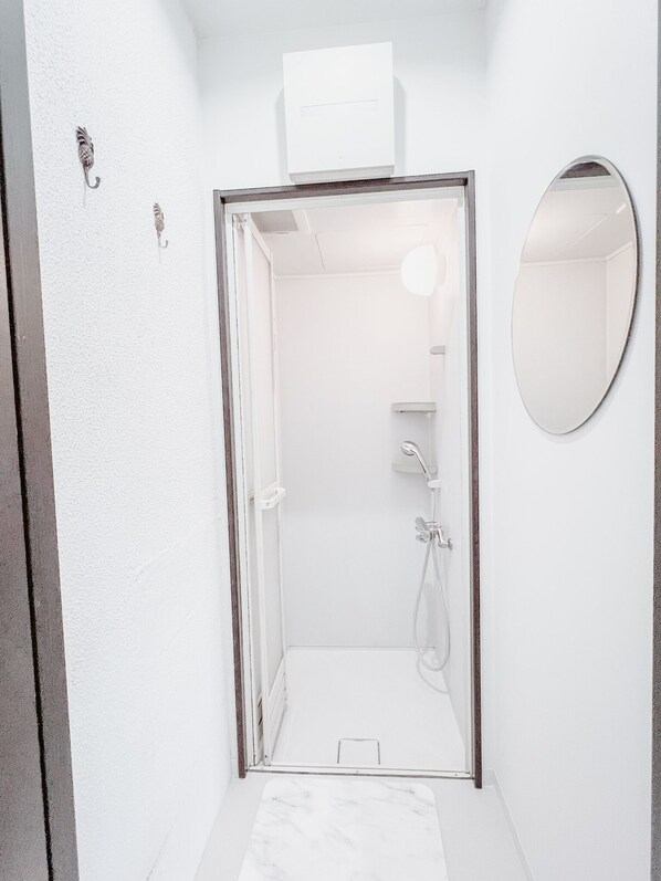 A modern bathroom with a shower, a mirror, and a towel rack.