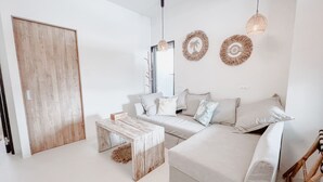 A modern living room with a sofa, coffee table, and decorative wall hangings. - BeachHouse Geragera (Kobe)