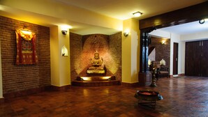 Un vestíbulo con pared de ladrillo, una estatua y una fuente.