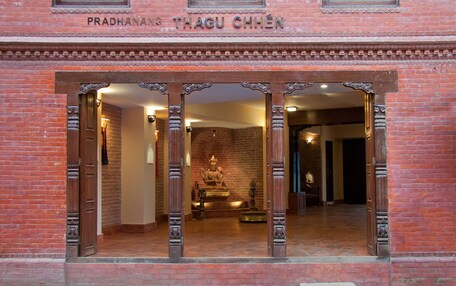 A traditional building with a sign reading "Pradhanans Thagu Chhen".