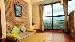 Una habitación acogedora con pared de ladrillo, un ventanal con cortinas, una cama con almohadas y vistas a la ciudad.