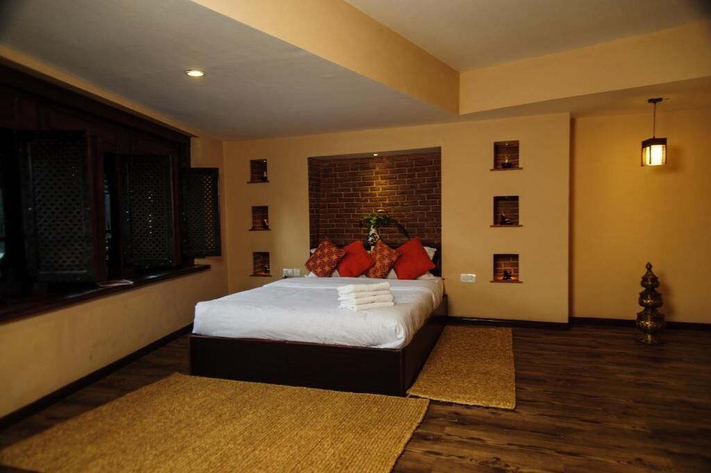 Un dormitorio con una cama grande, una pared decorativa de ladrillo y una ventana pequeña.