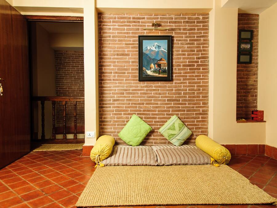 Ein Zimmer mit Backsteinwand, einem gerahmten Bild, einem Bett mit Kissen und einer Holztür.