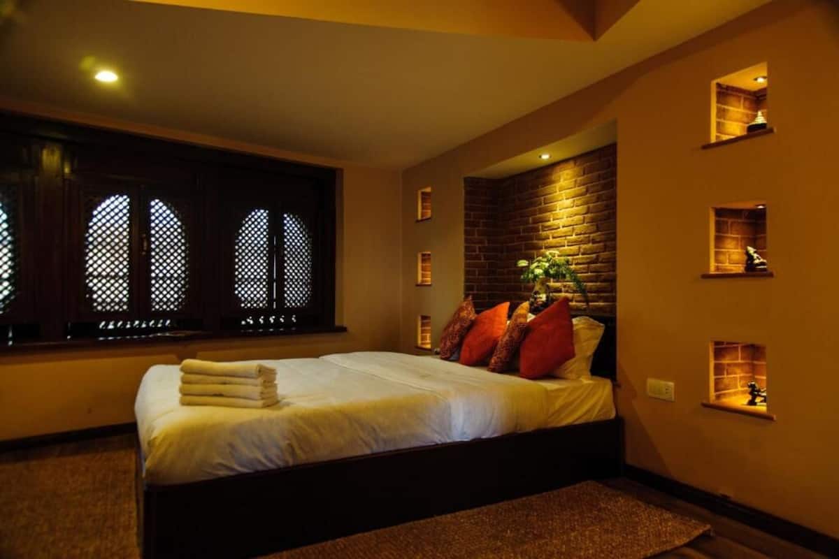 A bedroom with a large bed, a brick accent wall, and built-in shelves with decorative items.