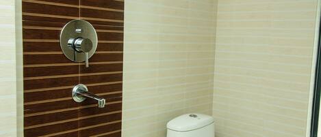 Un baño con pared de paneles de madera, inodoro blanco y ducha.