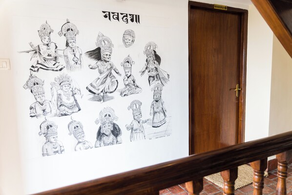 A wall with black and white sketches of figures, a wooden door, and a staircase railing.