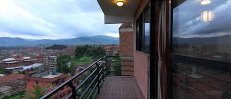 Un balcón con vistas a la ciudad y montañas.