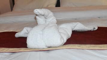 A bed with a white, fluffy, stuffed animal-like object in a reclining position.