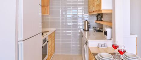 A modern kitchen with wooden cabinets, a built-in oven, a sink, and a dining area with a table set for four.