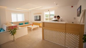 A modern living room with a sofa, coffee table, and a TV. - Hotel Aysima (Kas)