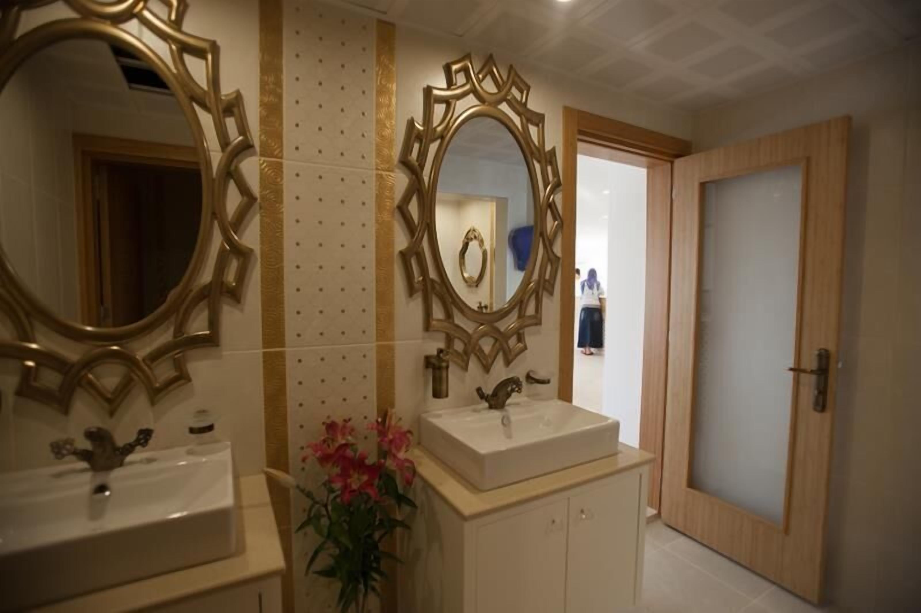A bathroom with two sinks, a large ornate mirror, and a wooden door.