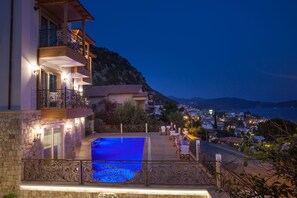 A hotel with a swimming pool, outdoor seating, and a view of the town and mountains. - Hotel Aysima (Kas)