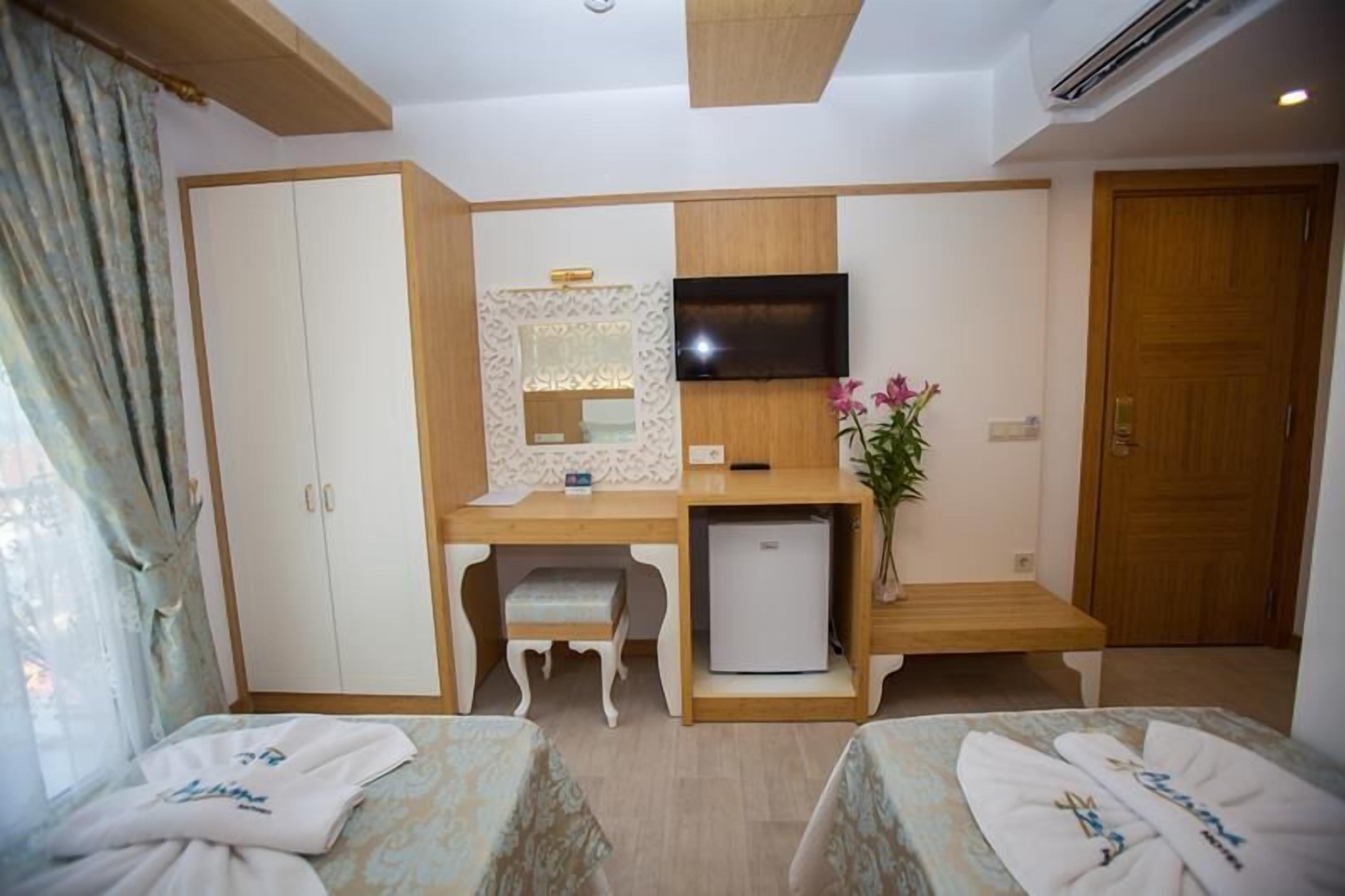 Een hotelkamer met een bed, een bureau met een televisie, een kleine koelkast en een kledingkast.
