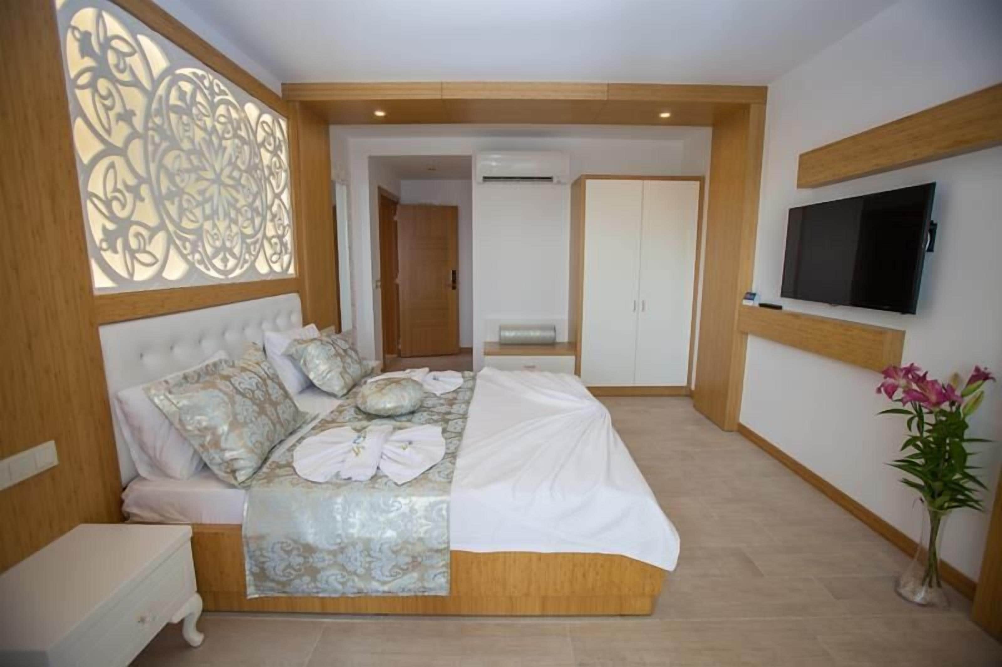 Ein Schlafzimmer mit einem großen Bett, einem an der Wand montierten Fernseher und einem dekorativen Raumteiler.