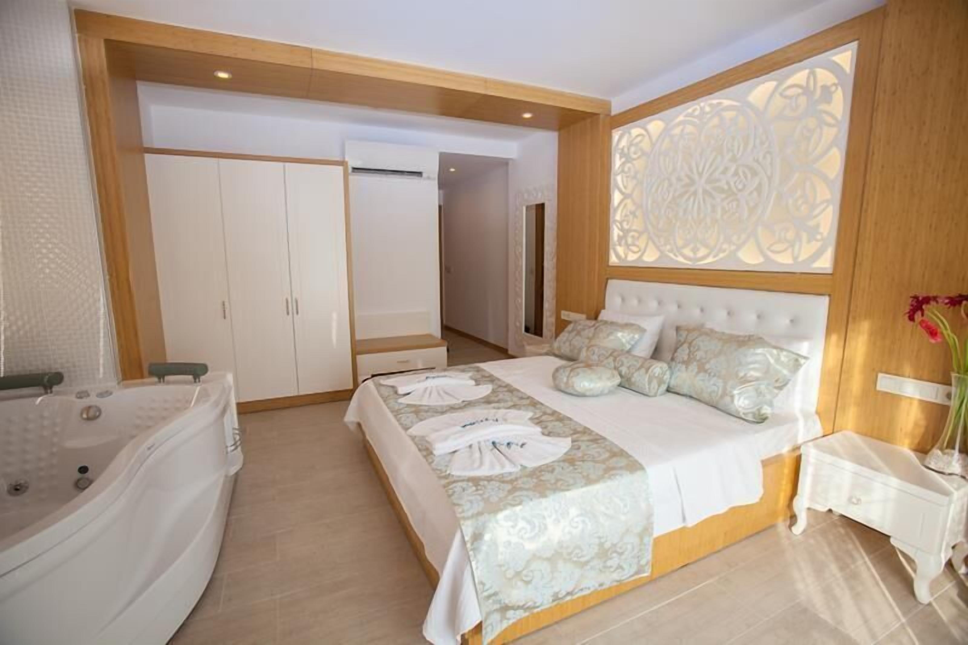 Une chambre avec un grand lit, une salle de bain séparée avec une baignoire et un dressing.