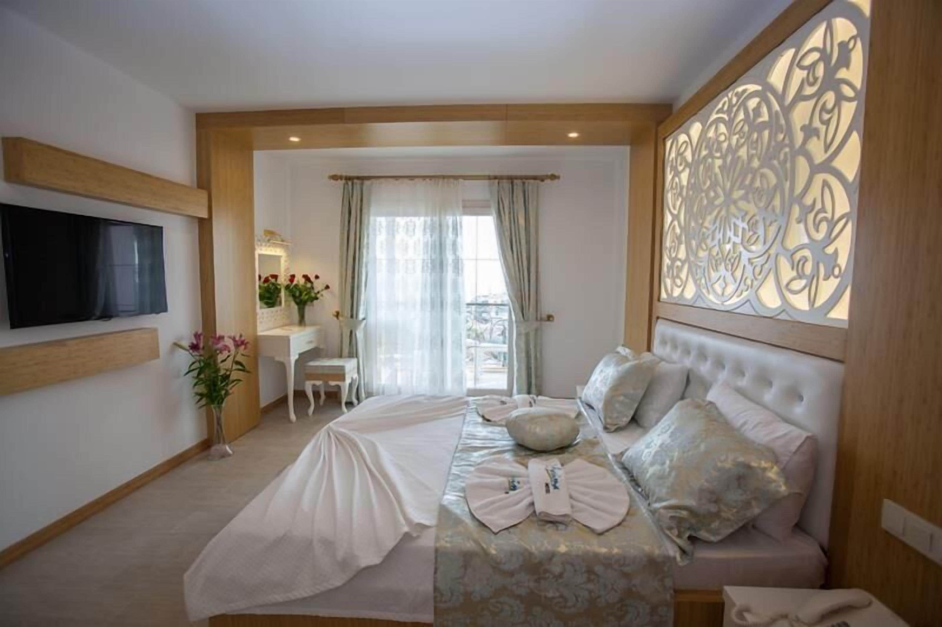 A hotel room with a bed, a desk, a chair, a TV, and a decorative wall panel.
