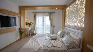A hotel room with a bed, a desk, a chair, a TV, and a decorative wall panel.