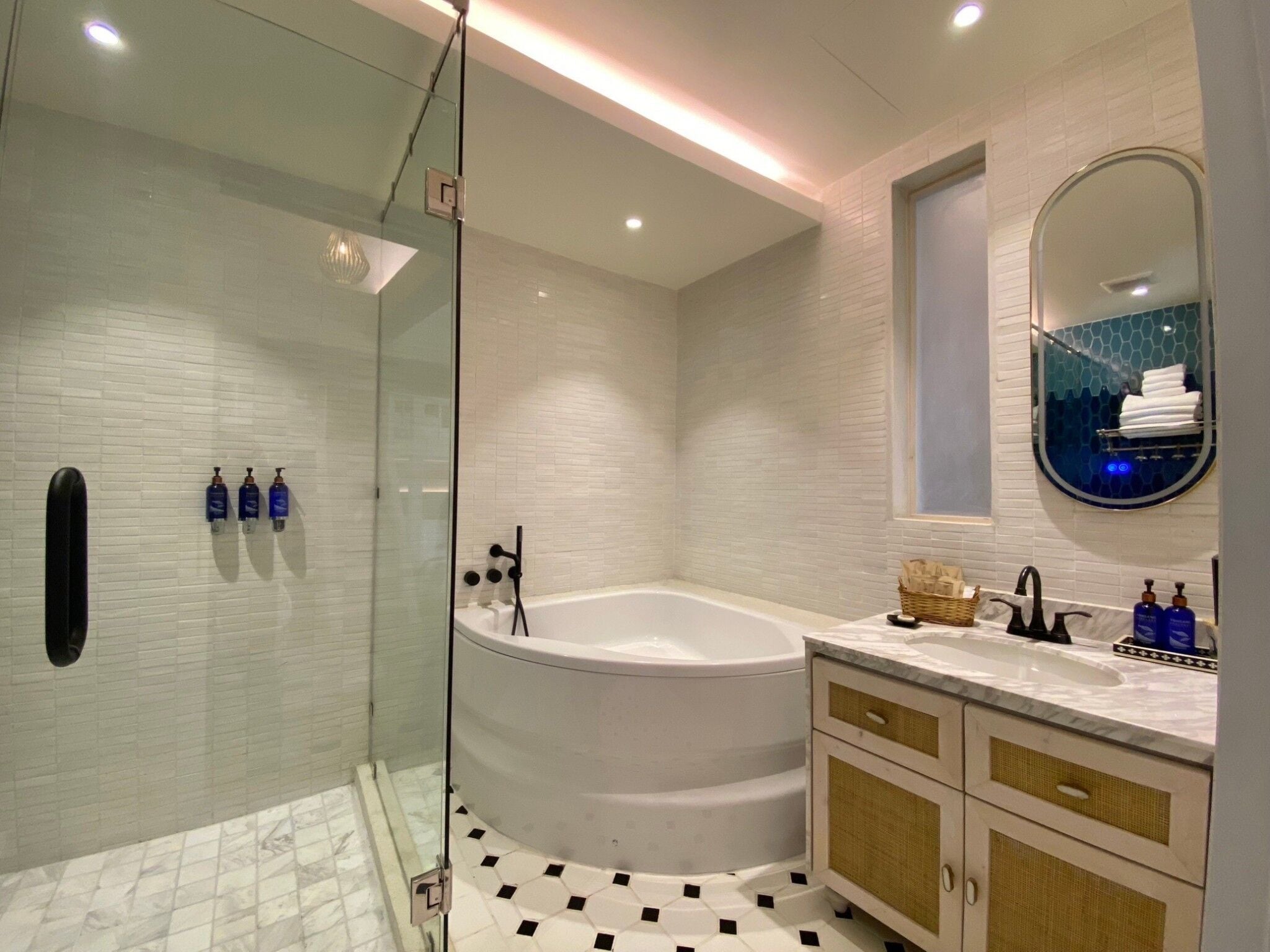 Un baño moderno con cabina de ducha de vidrio, una bañera independiente y un lavamanos con espejo.