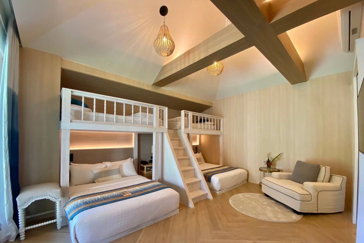 Une pièce comprenant un lit superposé, un canapé, une petite table et un escalier.