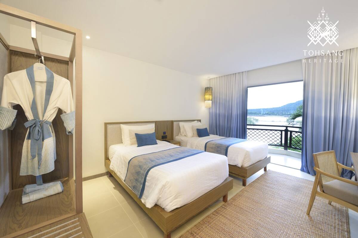 Une chambre d’hôtel avec deux lits, un balcon avec vue et un porte-peignoir.