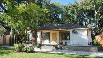 A single-story house with a tiled roof, a front porch, and a small garden area.