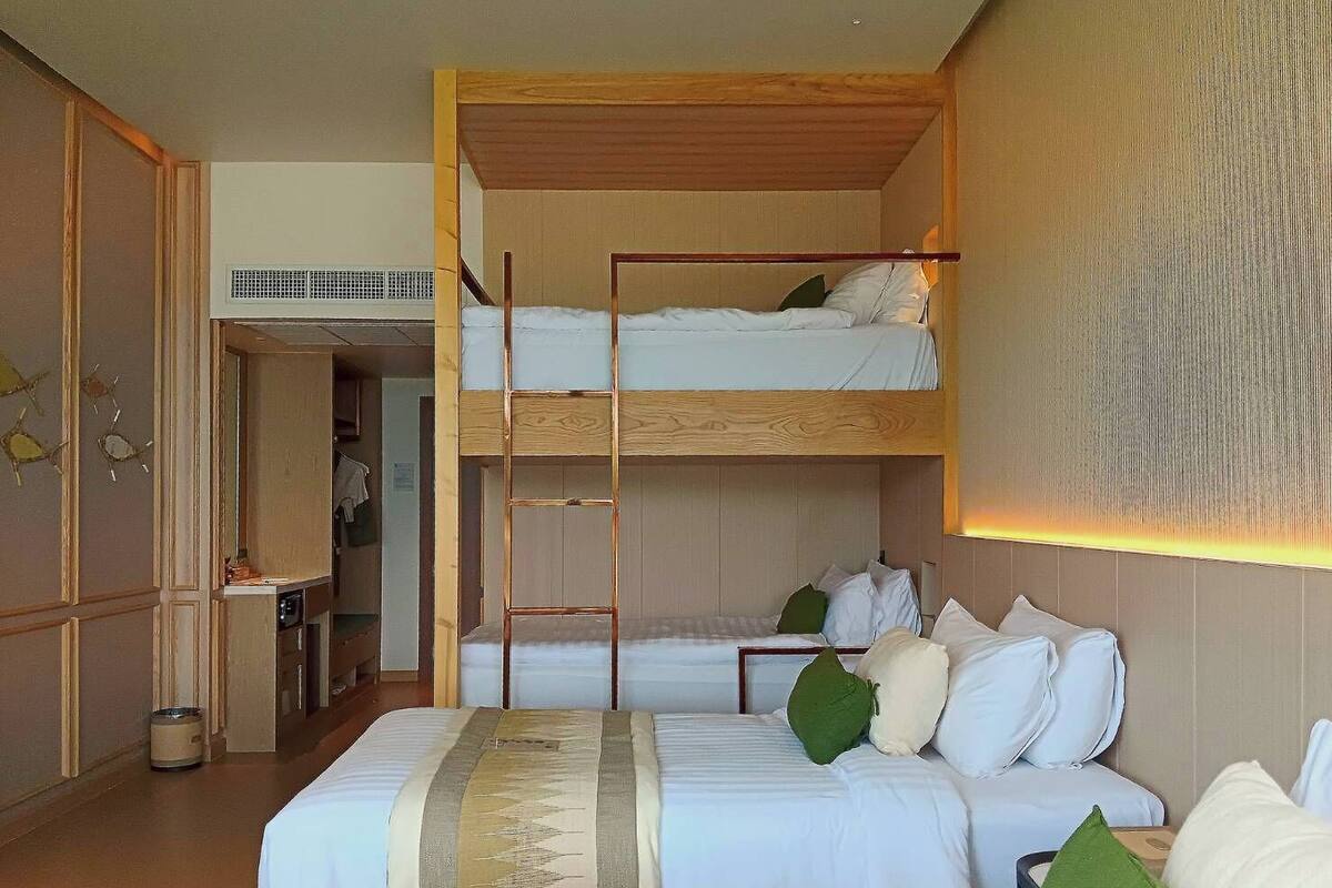 Une chambre avec un lit superposé, une échelle en bois, un bureau et une chaise.