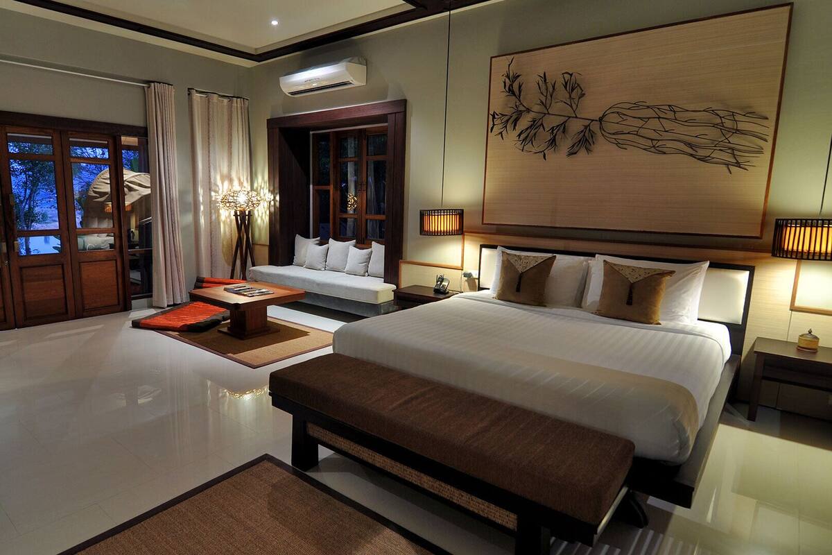 Une chambre spacieuse avec un grand lit, un coin salon et une vue sur l’extérieur.