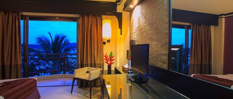Habitación de hotel con balcón, televisión, sofá y mesa.