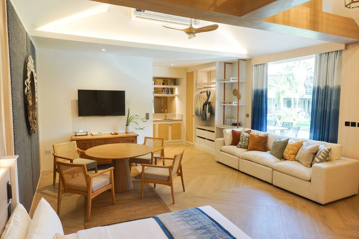Une chambre d’hôtel moderne dotée d’un coin repas, d’un canapé et d’une télévision.