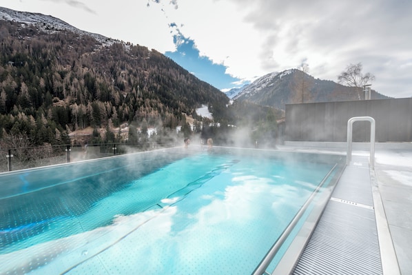 Una piscina al aire libre, una piscina infinita, sombrillas