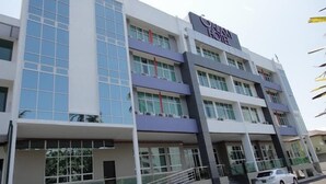 Um hotel de vários andares com design moderno, com grandes janelas e uma placa chamativa com o nome "Galaxy Hotel".