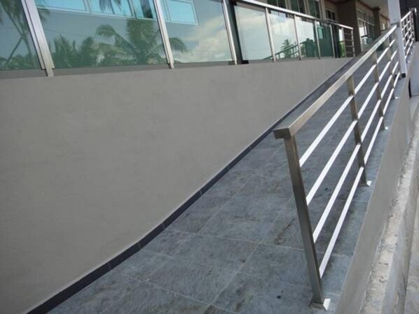 A modern building with a glass facade, a metal railing, and a tiled floor. - Galaxy Hotel (Simpang Ampat)