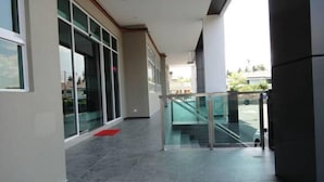 Um edifício moderno com galeria coberta, janelas amplas e guarda-corpo de vidro.