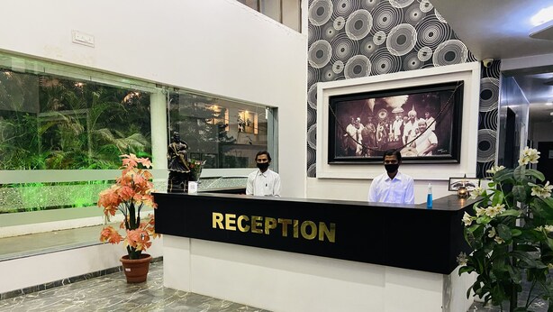Una mesa de recepción con un cartel que dice 'RECEPTION', una fotografía enmarcada en la pared y plantas en macetas.