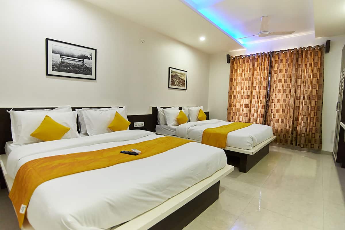 A hotel room with two beds, each with white bedding and yellow accents, a ceiling fan, and a framed picture on the wall.