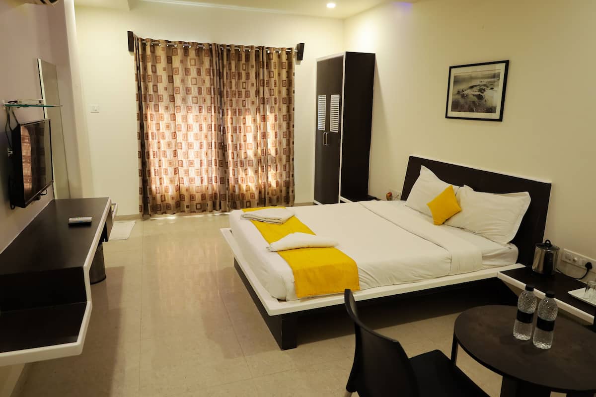 A hotel room with a bed, a desk, a chair, a TV, a wardrobe, and a picture on the wall.